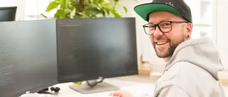 Person sitzt an einem Bürotisch vor 2 Bildschirmen.