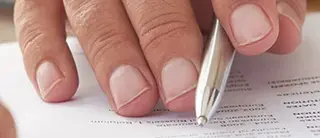 Kugelschreiber wird zur Vertragsunterschrift in der Hand gehalten